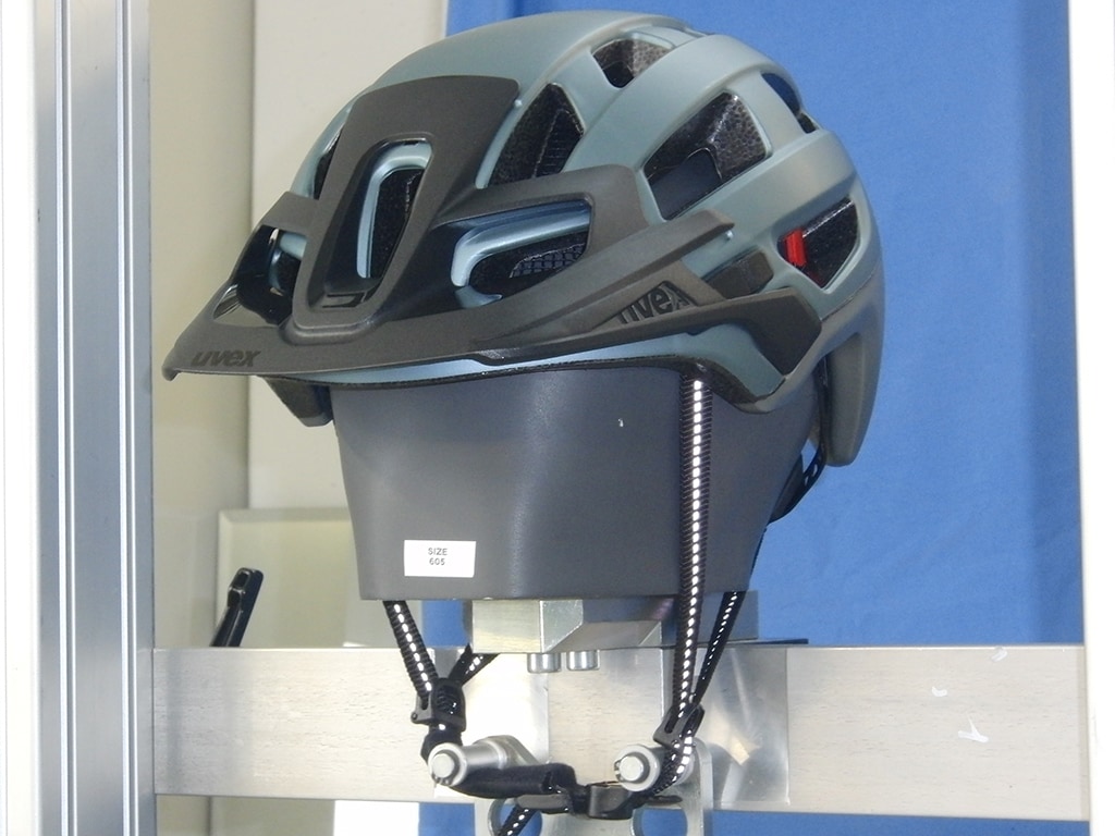 Uvex-Helm schräg von vorn auf Metallkopf mit gestreckten Kinnriemen
