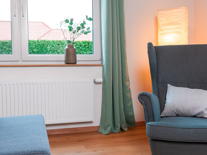 Wohnzimmer mit Heizung an der ein smartes Thermostat angebracht ist