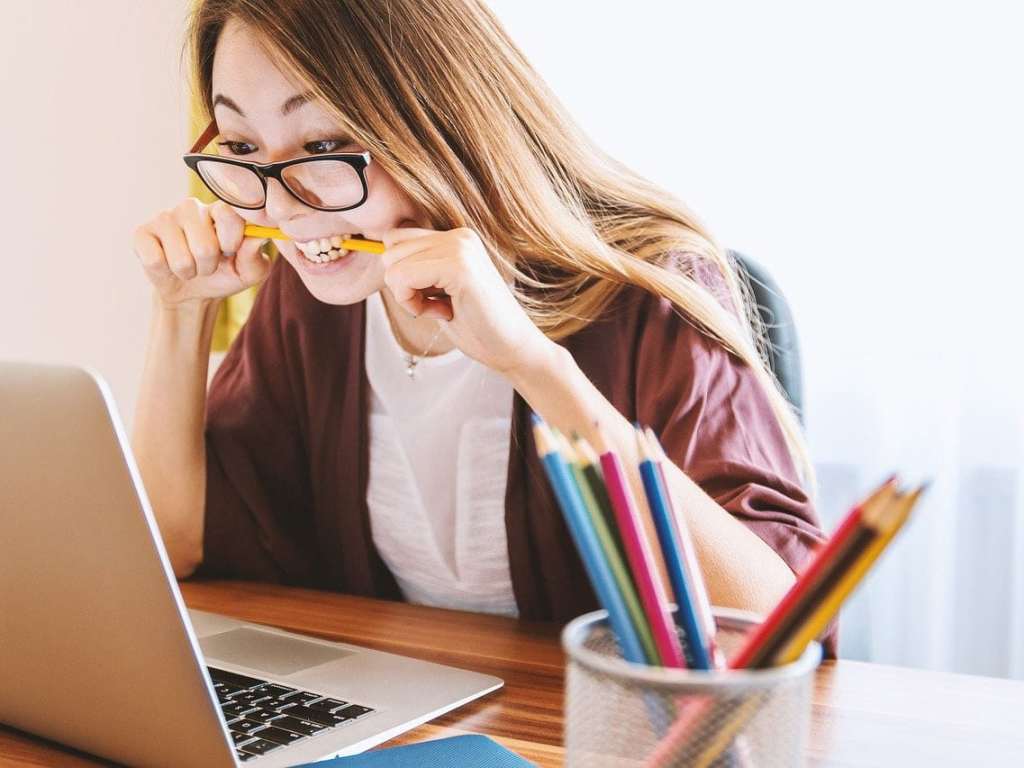 Frau am Notebook beißt in ihren Stift wie in einen Knochen.