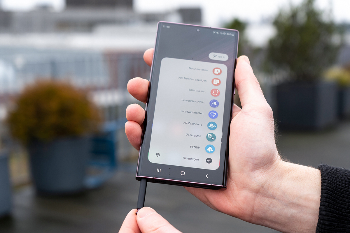 Hand hält Samsung Galaxy S22 Ultra während andere Hand Stift unten rauszieht