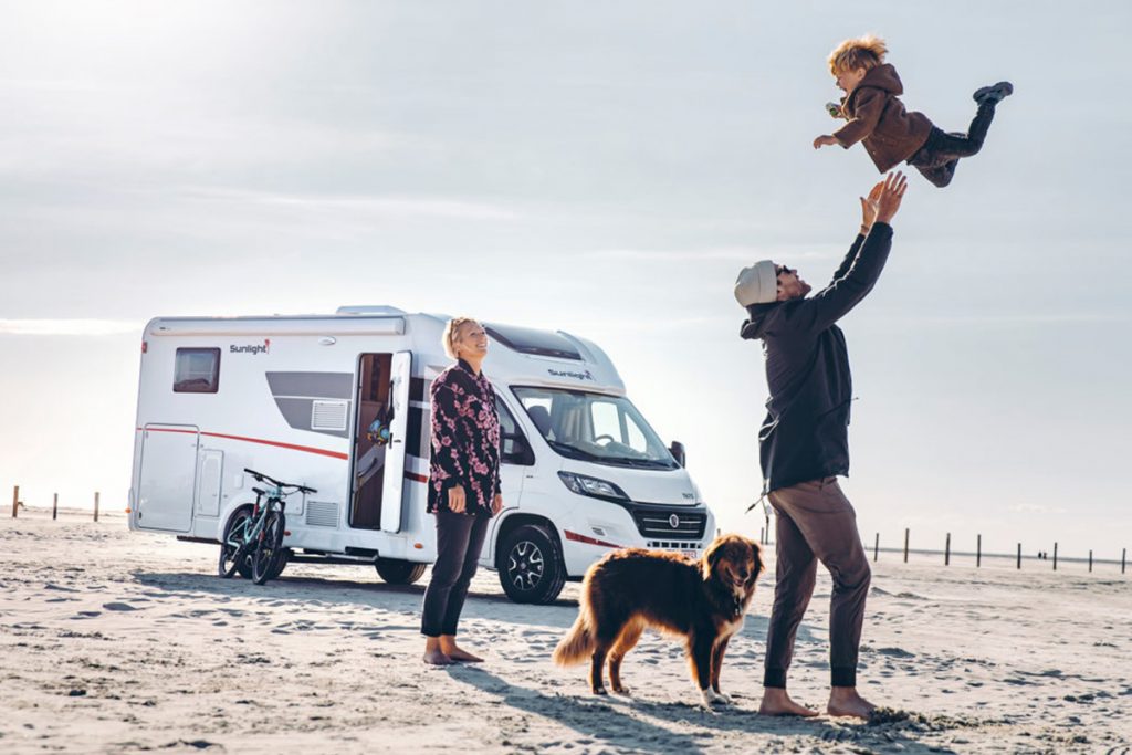 Eine Familie mit Hund vor einem Wohnmobil