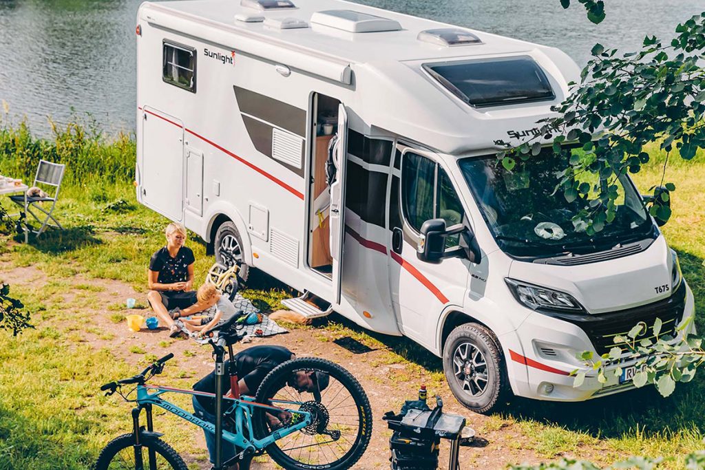 Ein Fahrrad und mehrere Personen neben einem Wohnmobil