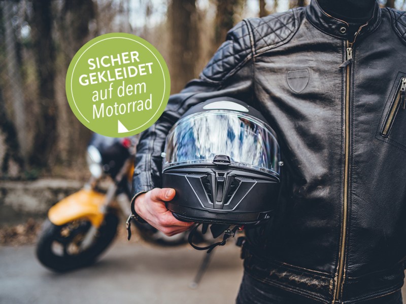 Ein Mann hält einen Motorradhelm unter dem Arm