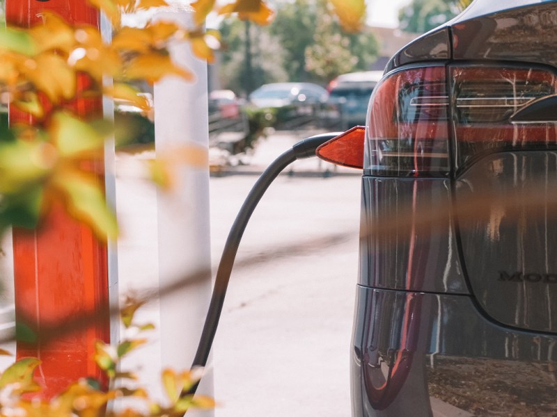 Tesla im Anschnitt von hinten, wird an Supercharger geladen