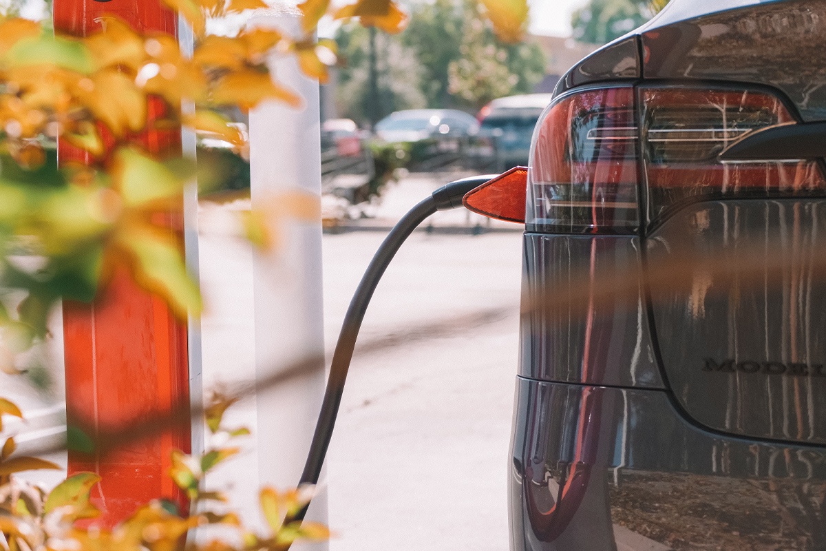 Tesla im Anschnitt von hinten, wird an Supercharger geladen