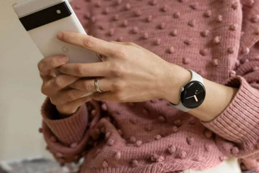 Frau trägt Google Pixel Watch und hält ein Google Pixel Smartphone in der Hand.