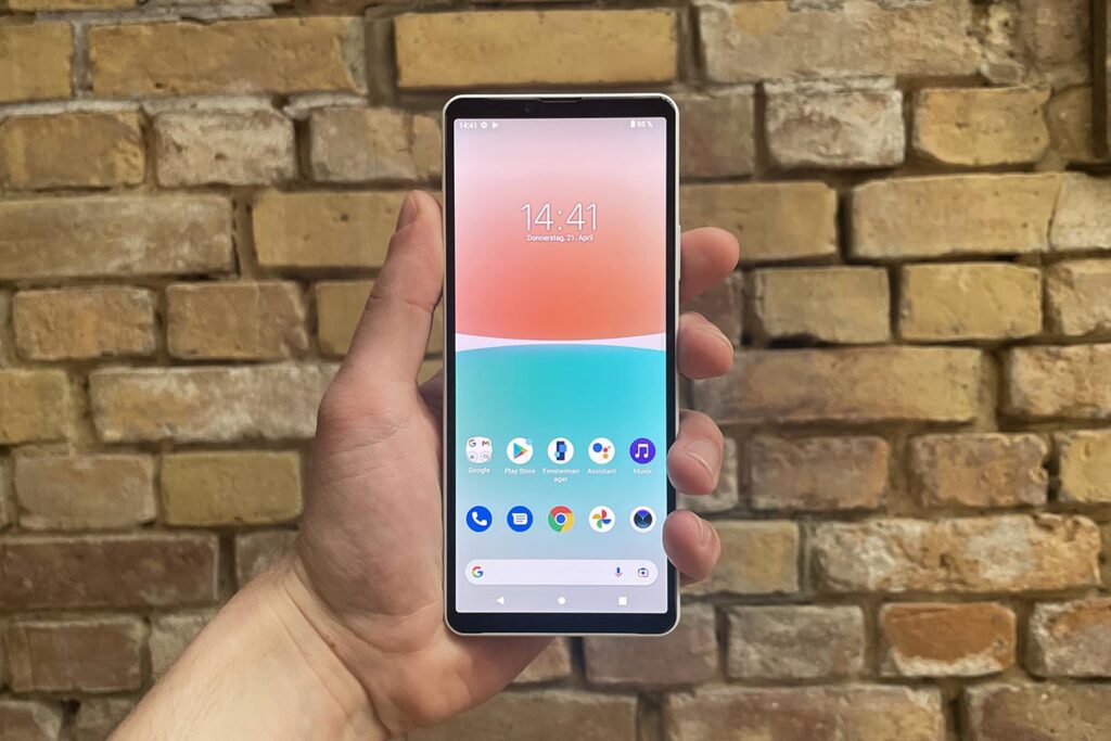 Eine Hand hält das Sony Xperia 10 IV vor einer Backsteinwand.