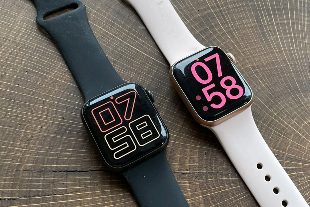 Zwei Apple Watches in dunkel und hell nebeneinander auf Holztisch