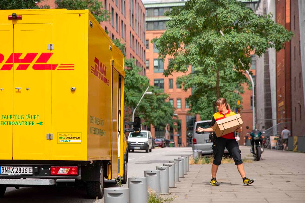 Eine Postbotin schließt ein DHL-Fahrzeug in der Hafencity ab.