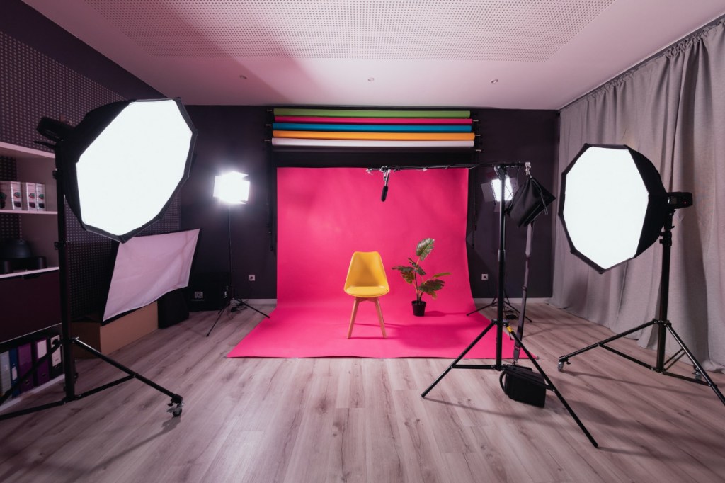 Studio mit zwei Softboxen an den Seiten und einem pinken Hintergrund mit gelben Stuhl in der Mitte