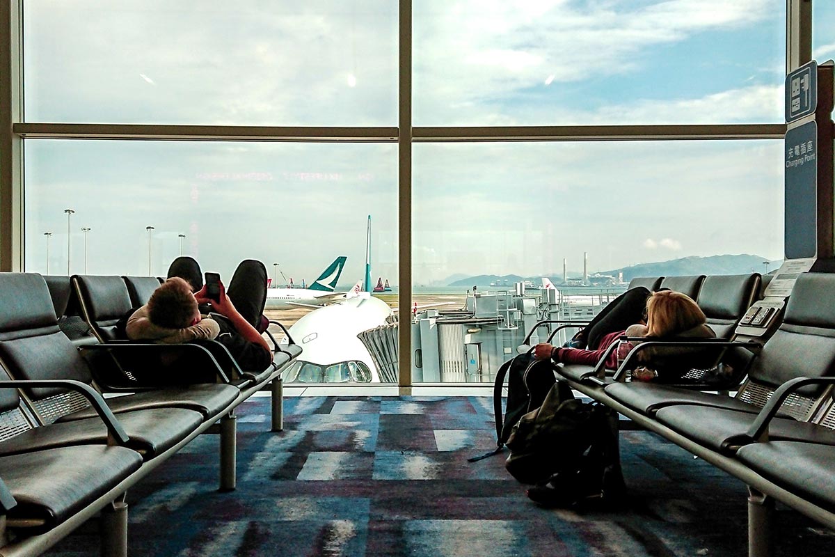 Zwei Menschen liegen auf Bänken im Flughafen