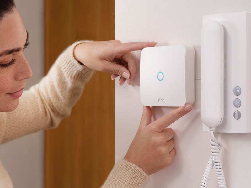 Frau verbindet die WLAN-fähige Gegensprechanlagen-Erweiterung Ring Intercom mit einer vorhandenen Gegensprechanlage an einer Wohnungstür.