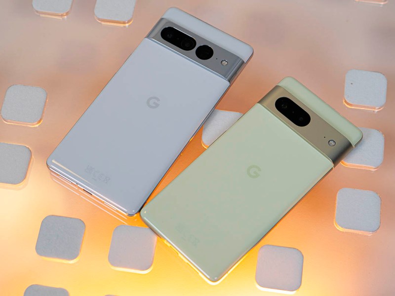 Google Pixel 7 und Pixel 7 Pro nebeneinander auf Glasplatte, gelblich hinterleuchtet