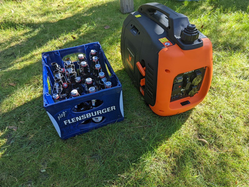 Der Fuxtec-Generator steh auf einer Wiese neben einem Bierkasten mit 0,33 Liter-Flaschen