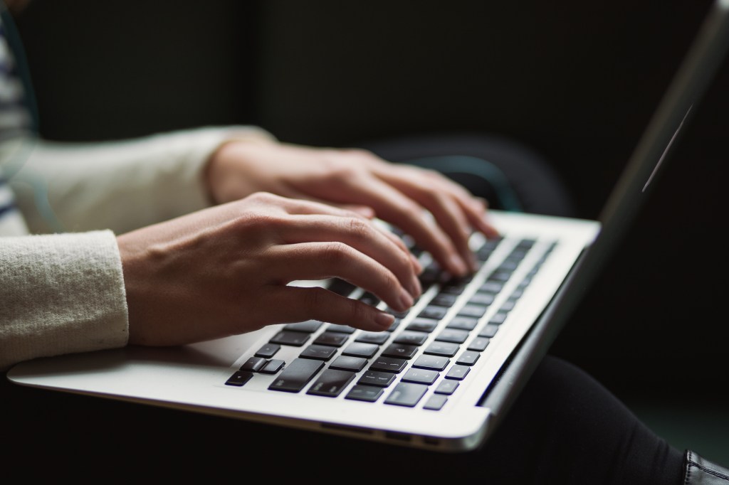 Mensch tippt auf Laptoptastatur