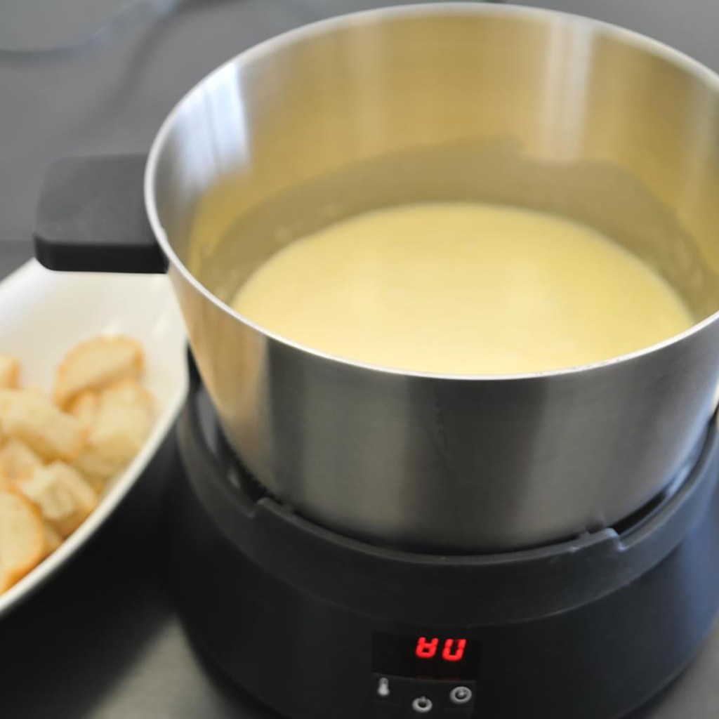 Topf mit Pudding auf kleiner runder Induktionsplatte von Fondue-Set