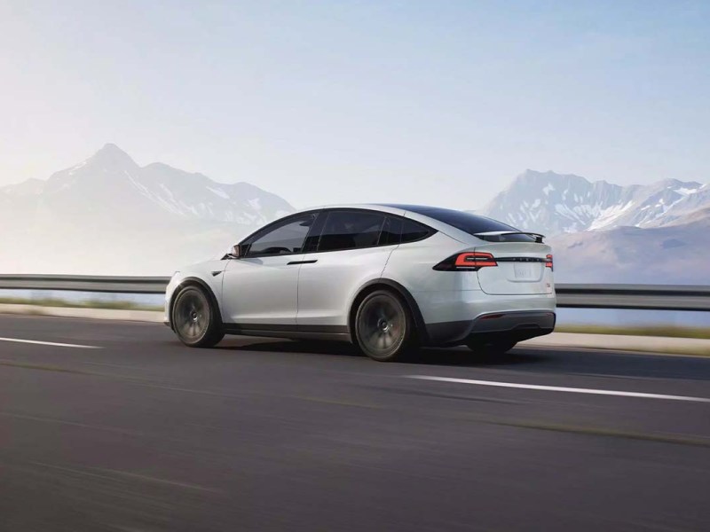 Grafik Tesla Model X auf einer leeren Straße, Bergpanorama im Hintergrund