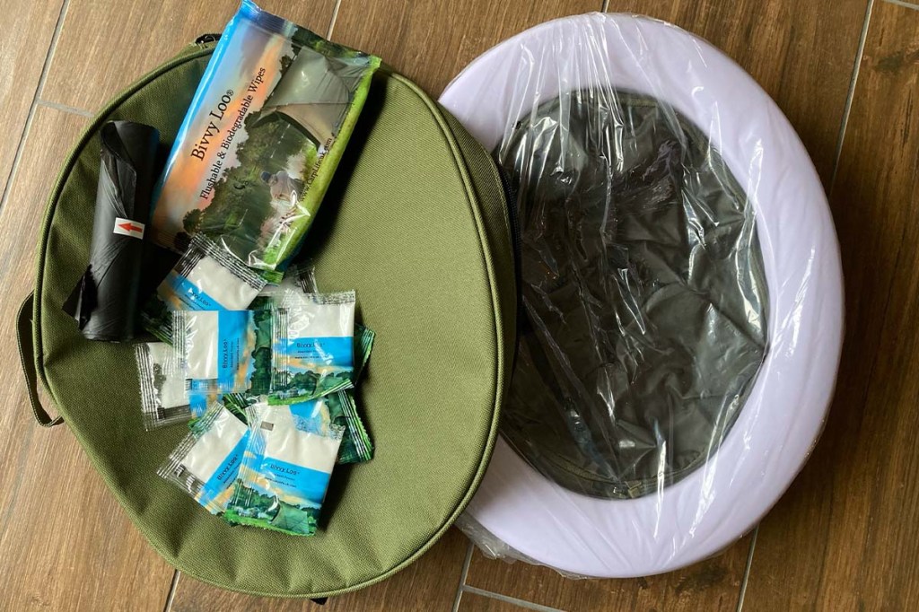 Campingtoilette BivvyLoo von CarpLife, verpackt neben Tragehülle liegend, dabei Absorberpulver, feuchtes Toilettenpapier und Müübeutel