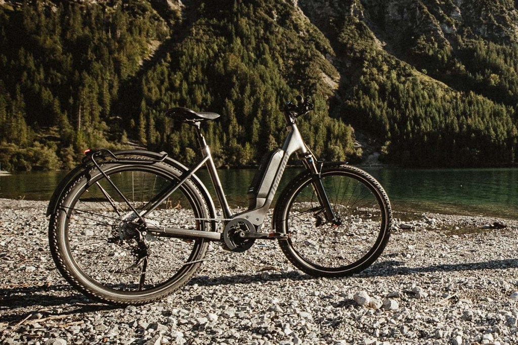 E-bike 138 von Diamant steht vor einem Fluss, im Hintergrund Berge