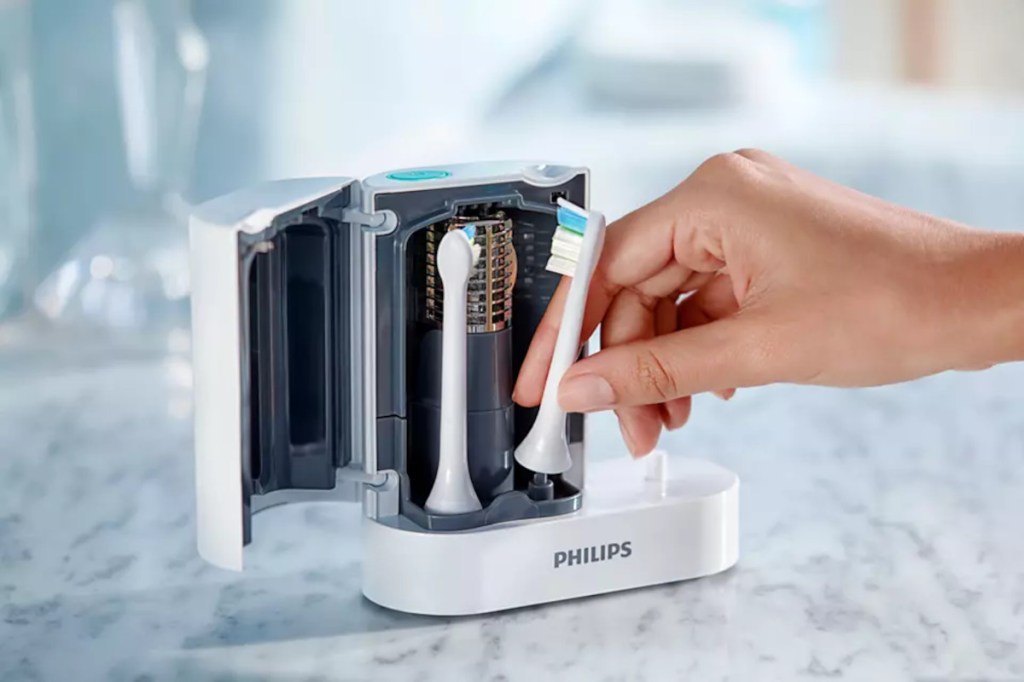 Weißes Gerät von Philips aufgeklappt mit Bürstenkopf für elektrische Zahnbürste wird von Hand reingesteckt