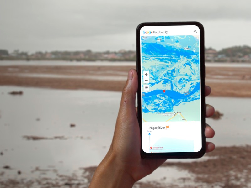 Die FloodHub-Anwendung auf einem Smartphone, im Hintergrund eine Flusslandschaft.