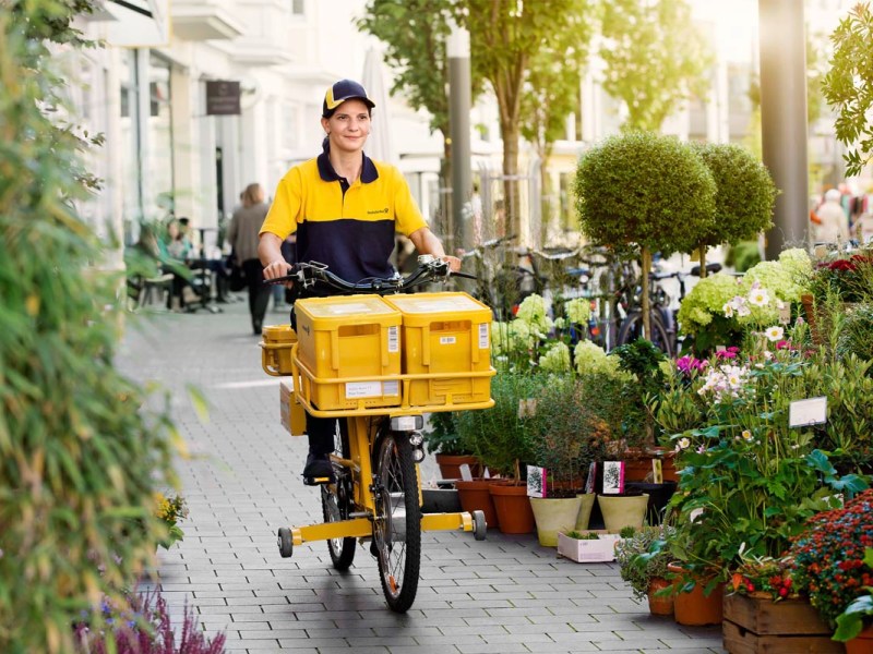 Briefzusteller bei der Zustellung auf einem Fahrrad.