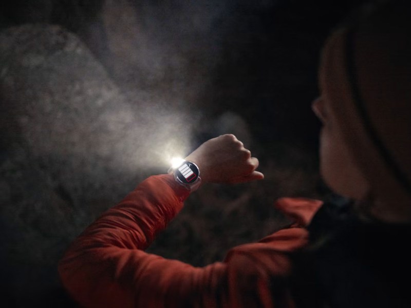 Eine Person schaut im Dunkeln auf die Garmin Smartwatch, die auch eine Taschenlampe integriert hat.