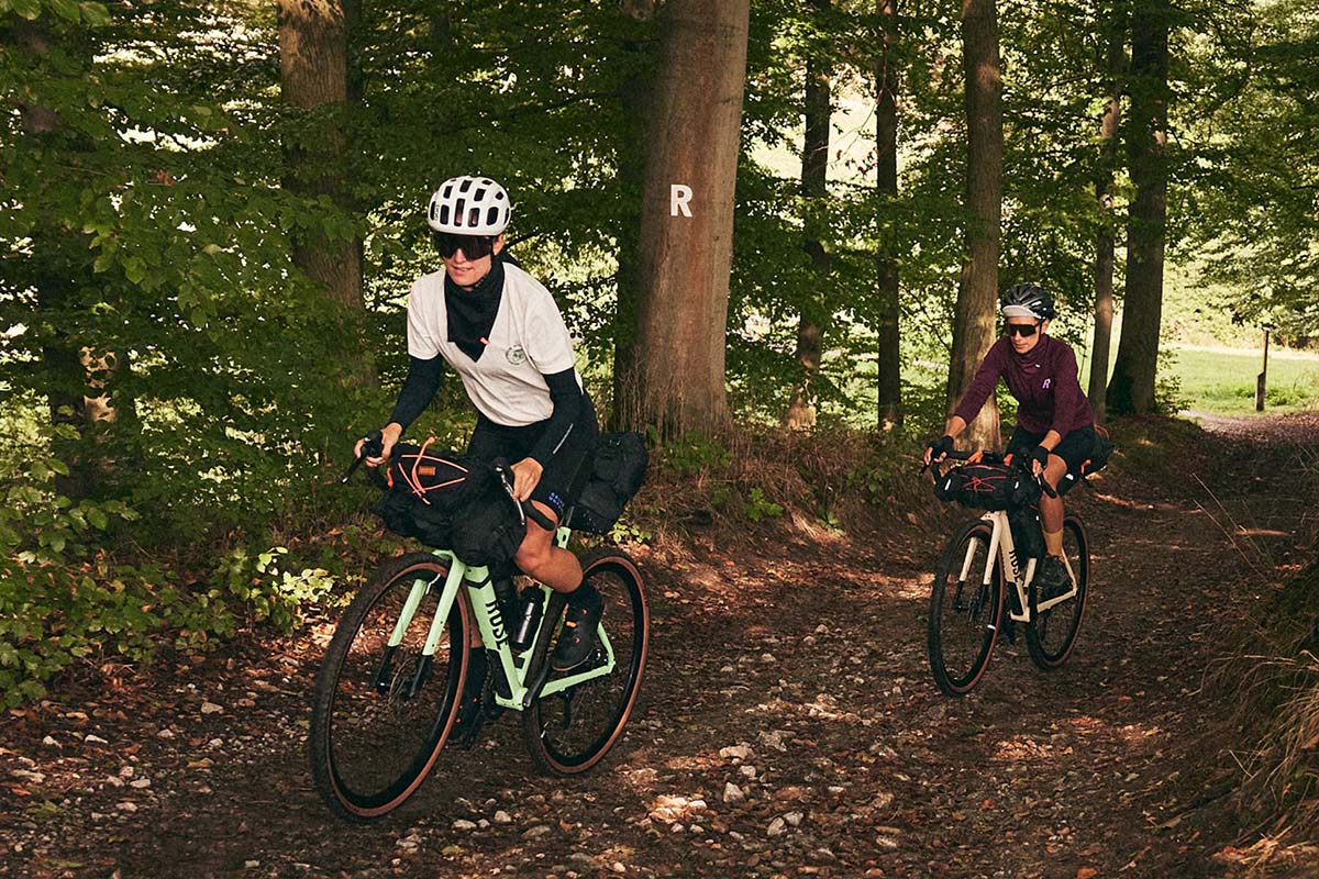 Zwei Personen fahren mit einem E-Gravelbike durch einen Wald