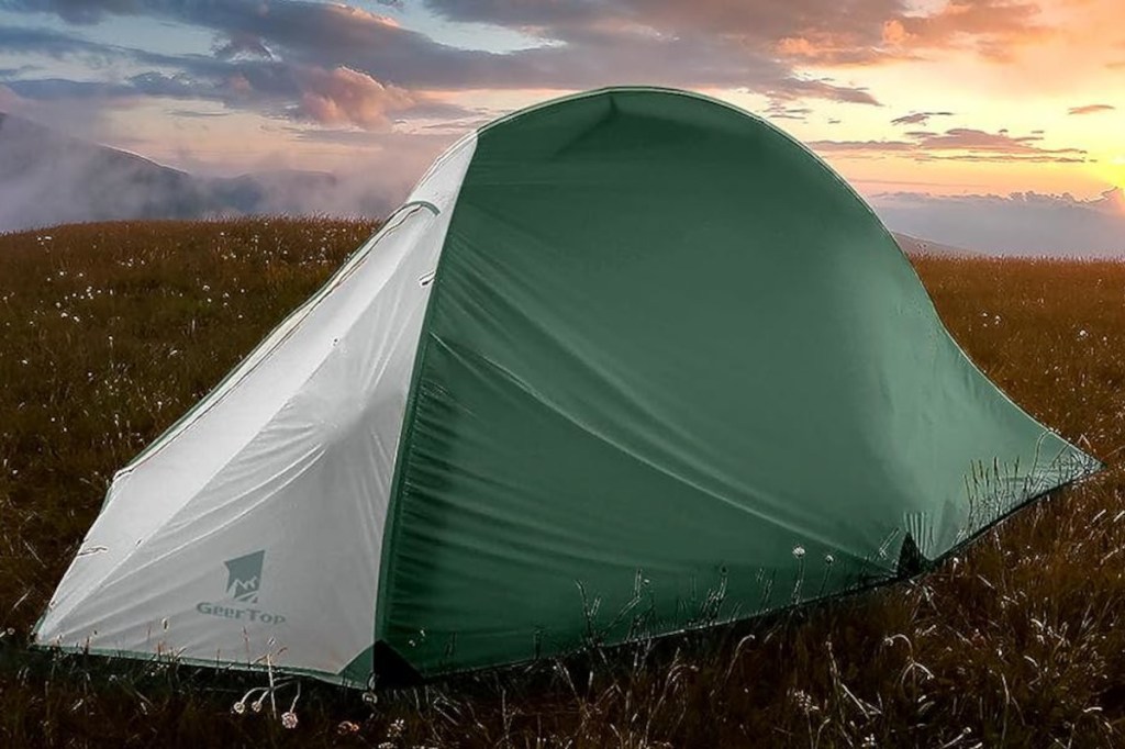 Grün weißes Kuppelzelt von Geertop auf Wiese vor bewölktem Himmel bei Sonnenuntergang