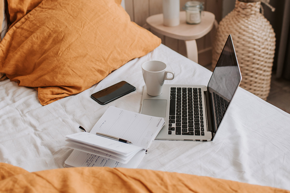 Ein Laptop und Schreibutensilien auf einem Bett.