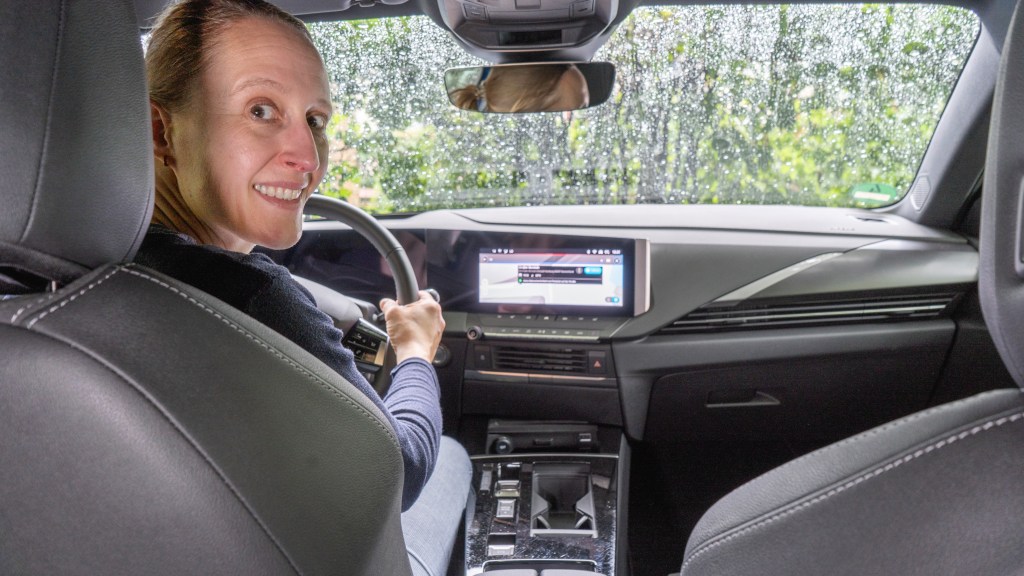 Fahrerin im E-Auto Opel Astra Electric schaut vom Fahrersitz in den Fond des Wagens.