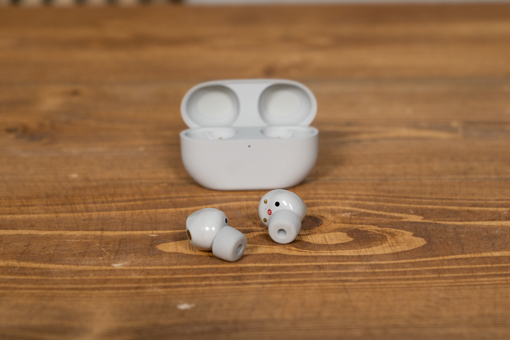 Die grauen Sony In-Ear-Kopfhörer vor ihrem Ladecase auf einem Holztisch.