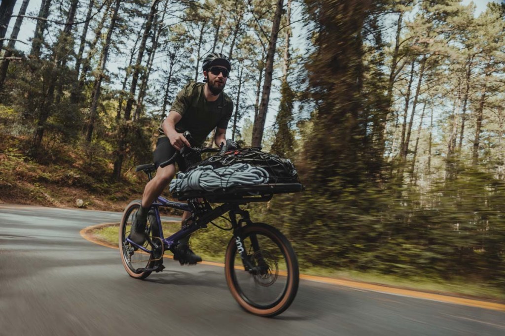 Mann fährt mit dem E-Bike Gravit Dust vollbeladen einen bergige Straße hoch