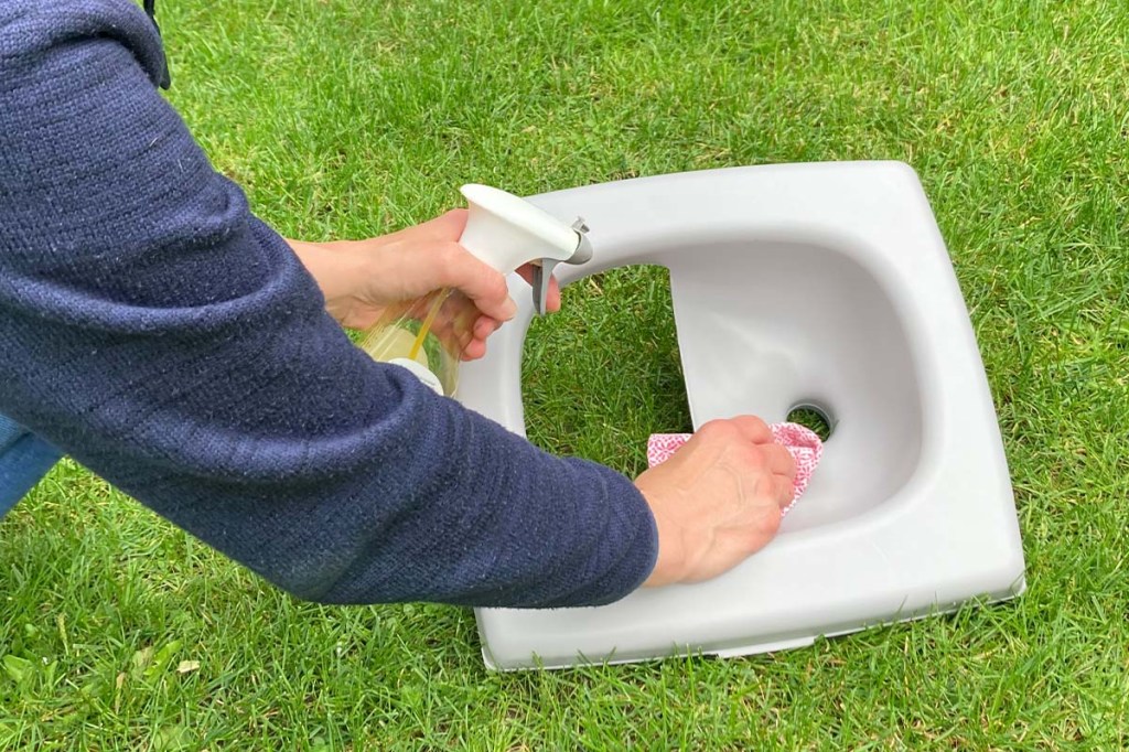 Nahaufnahme Trenneinsatz Trenntoilette, wird von einer Hand und Lappen gereinigt