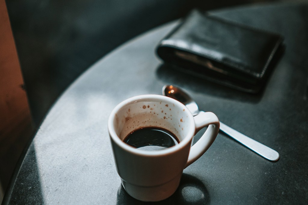 Eine Geldbörse neben einer Espresso-Tasse.