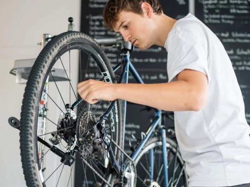 Person schraubt an einem Fahrrad.