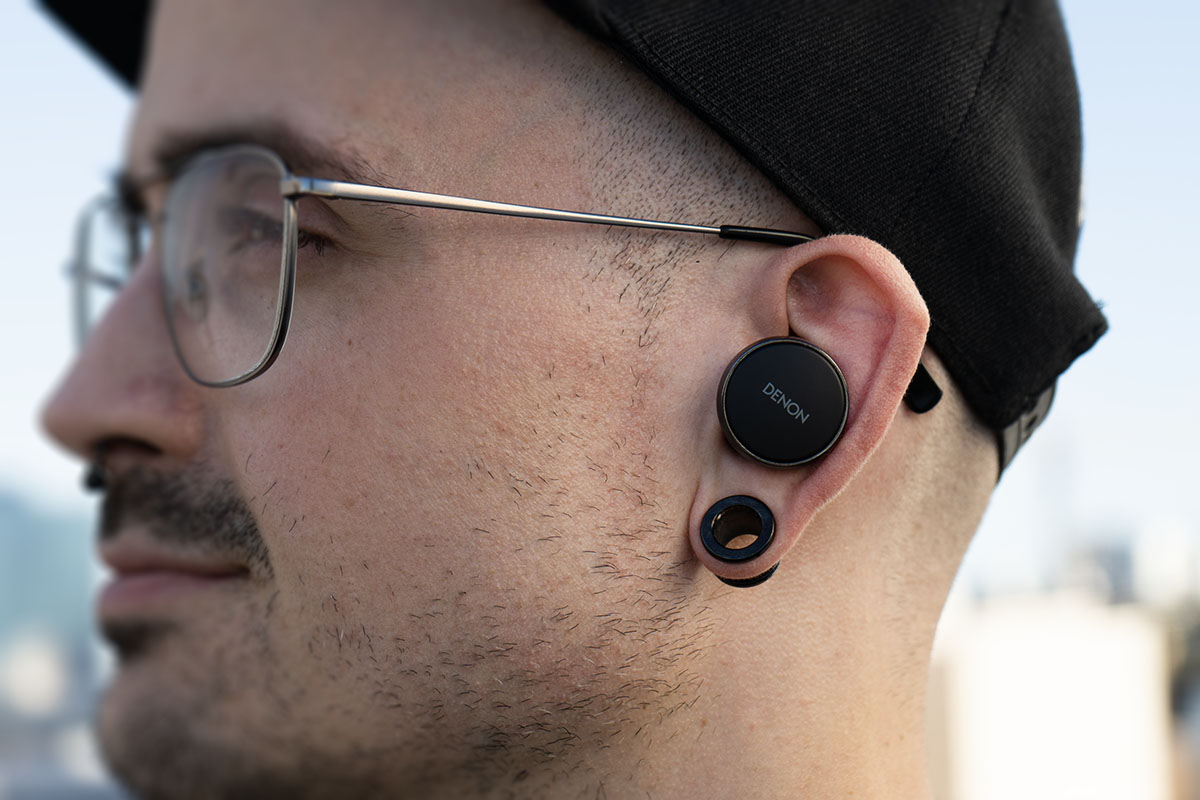 Der Testredakteur trägt die runden In-Ears Denon PerL Pro 182, seitlich fotografiert.