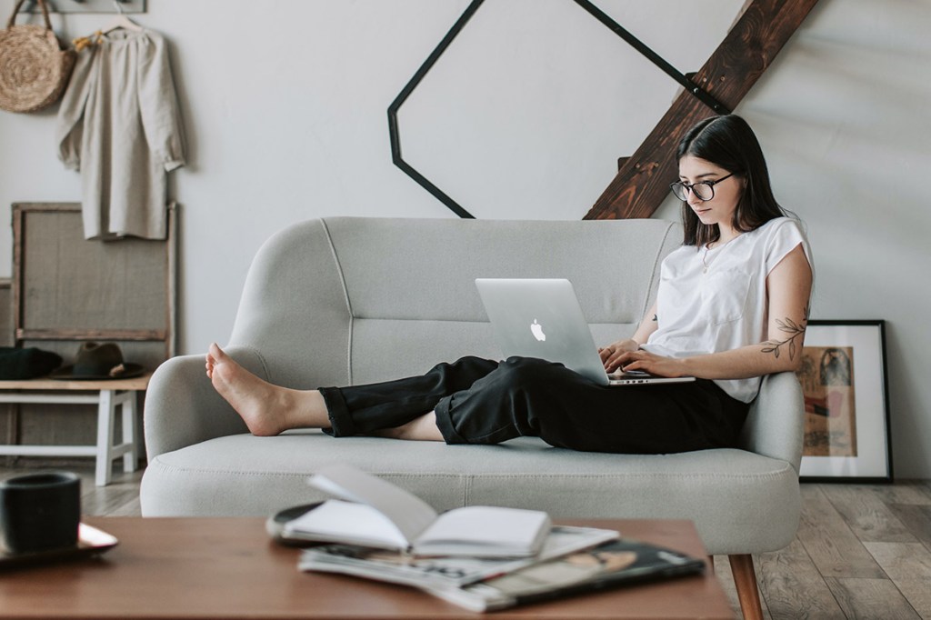 Eine Frau mit Laptop auf einem Sofa.