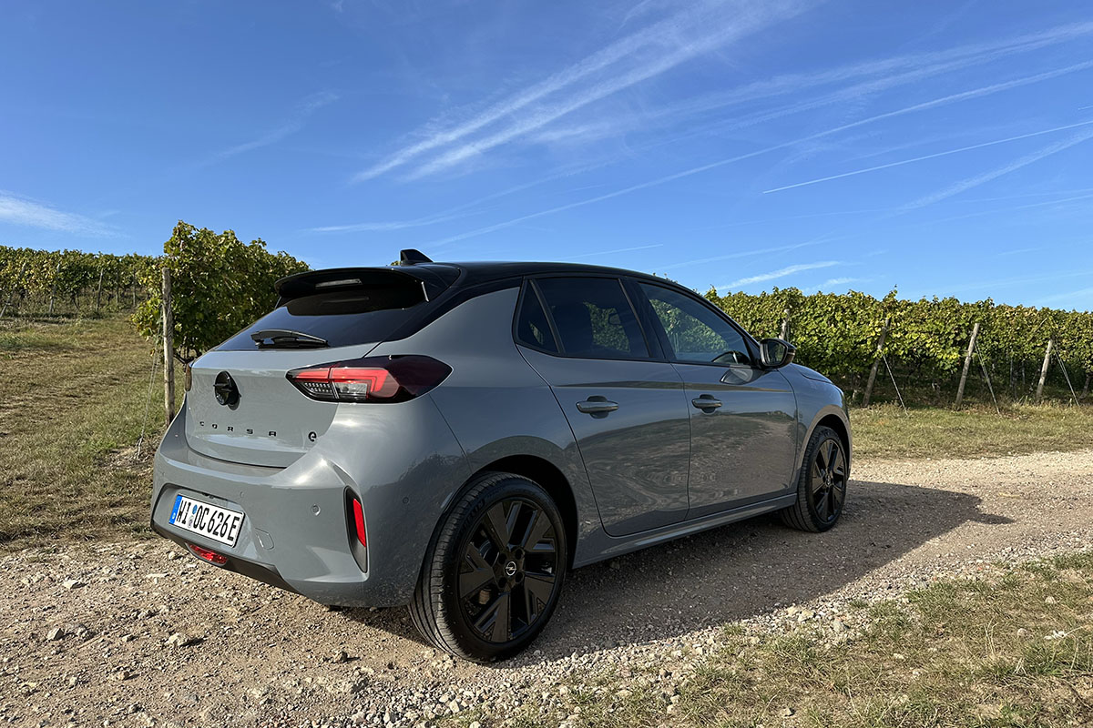 Von hinten schräge gesehen_: Opel E-Corsa mit geöffneter Fahrertür im Weinberg.