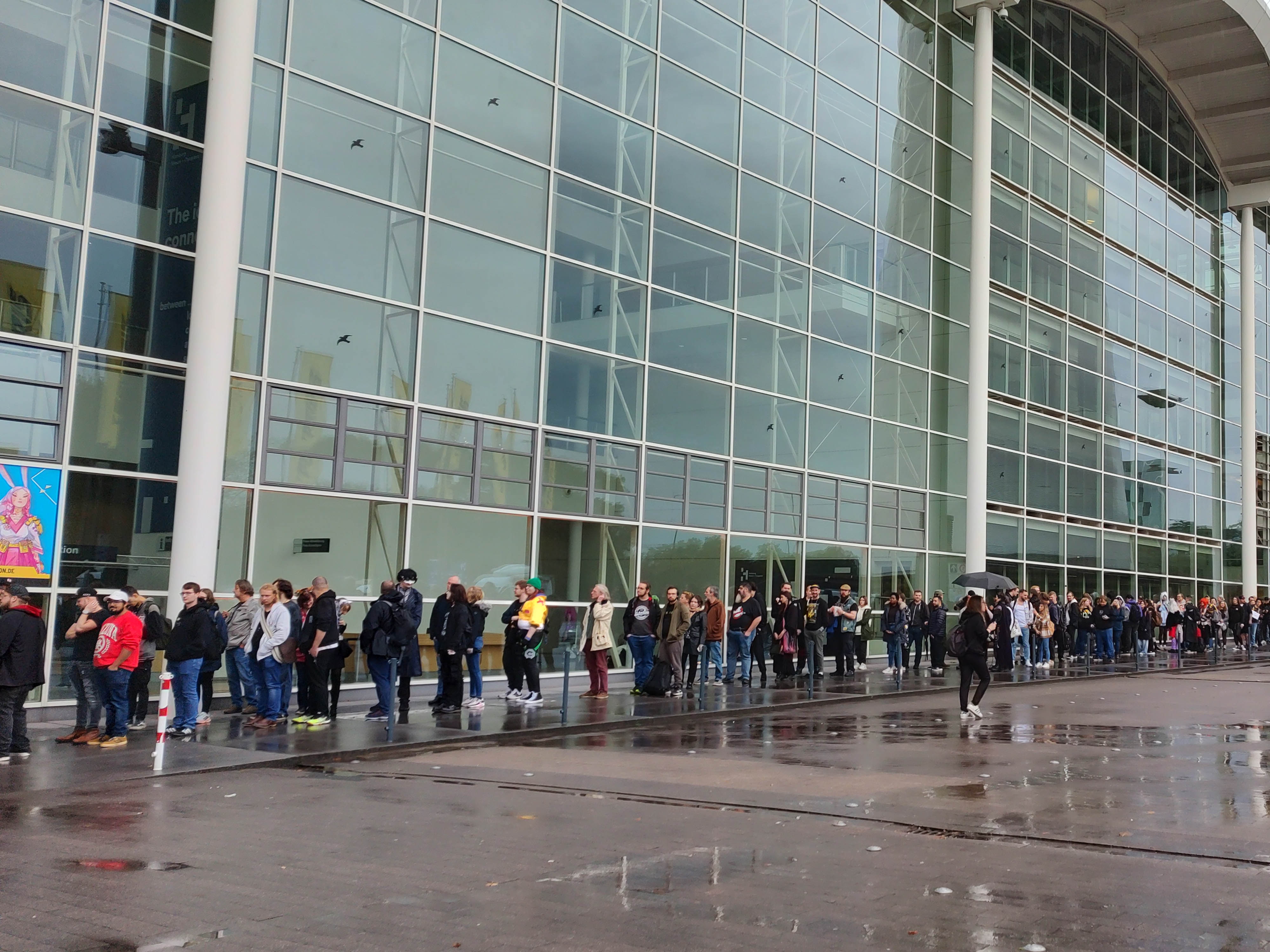 Viele Leute stehen in einer sehr langen Schlange am Gebäude vor der Hamburger Messe an.