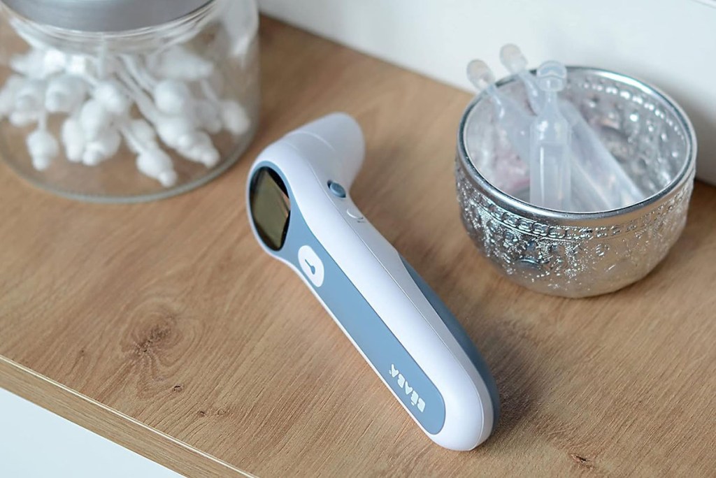 Ohrthermometer liegend auf Sidebord vor Medizin-Ampullen.