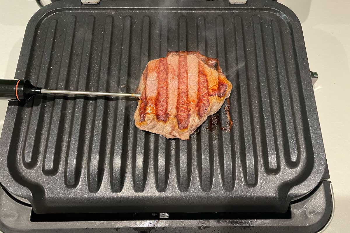 Ein gegrilltes Filet-Steak von unten auf der Garplatte des Tefal-Kontaktgrills mit Bratenthermometer.