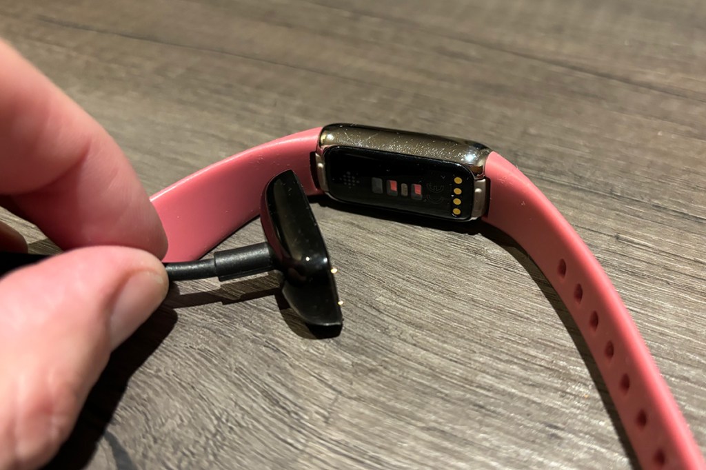 Der Fitness-Tracker Fitbit Luxe samt Ladegerät.