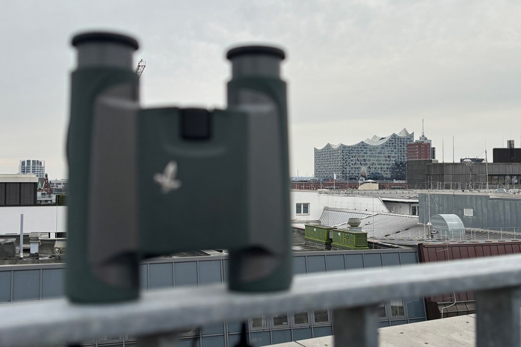 Unscharfes Swarovski-Fernglas im Vordergrund, die Hamburger Elbphilharmonie im Hintergrund.