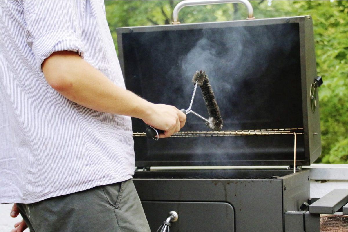 Person mit Zubehör für einen Grill in der Hand.