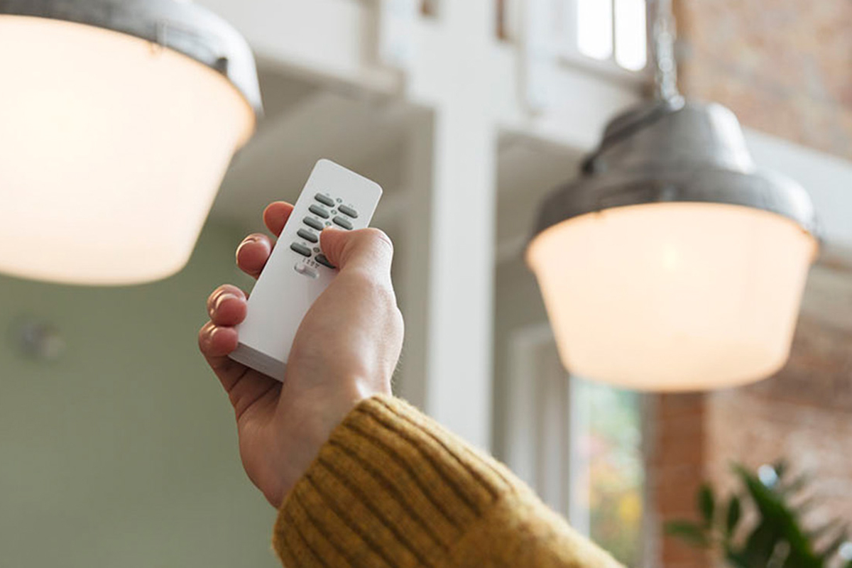 Hand mit Fernbedienung, die Lampen schaltet.