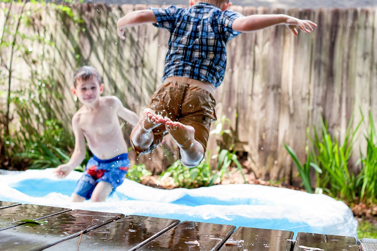 Zwei Kinder spielen in einem Pool im Garten.