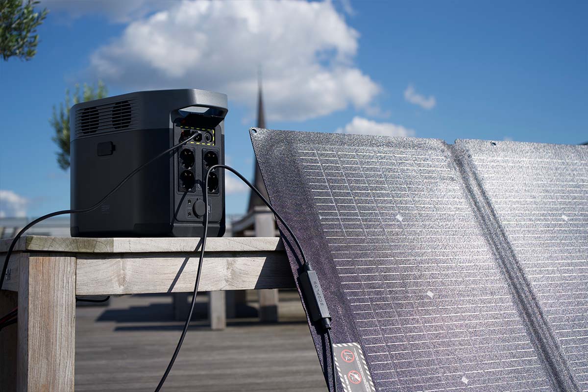 Die Delta 2 von EcoFlow auf einem Tisch im Outdoor-Setting. Davor steht ein Solarpanel.