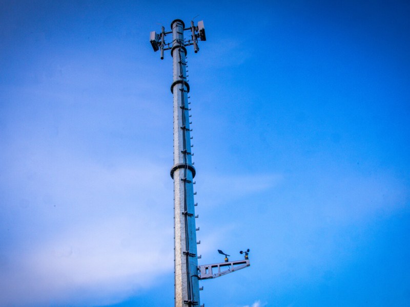 Ein Mobilfunkmast ragt in den blauen Himmel.