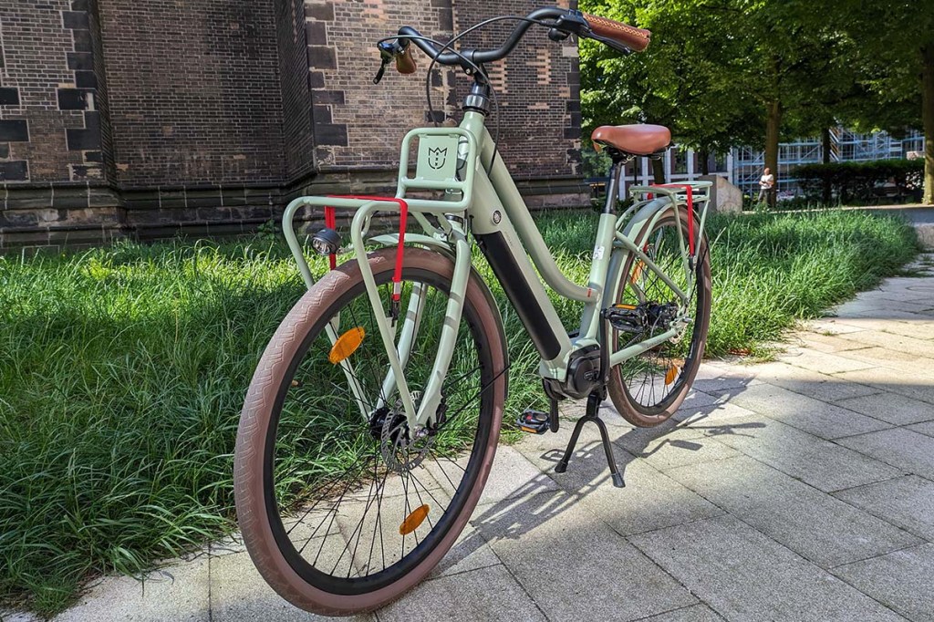 Grünes City-E-Bike auf einem Gehweg stehend